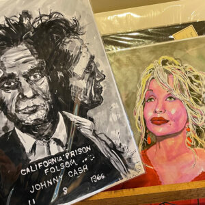 A photo of two fine art prints: watercolor drawings of Johnny Cash's mugshot and another of Dolly Parton.
