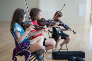 Three children playing fiddle.