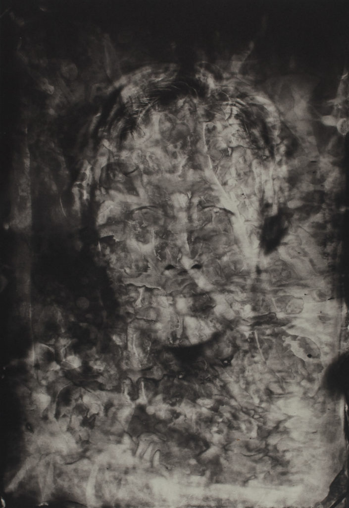 Through a haze of black, grey, and white ripples you can see the face of a white man with light-colored hair. This self-portrait has been manipulated so it is not wholly realistic.
