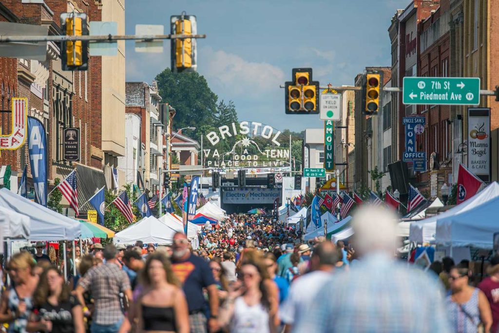 Photo of busy State Street in Historic Downtown Bristol, VA-TN -- filled with festivalgoers, vendor tents, and with the State Street sign in the background.